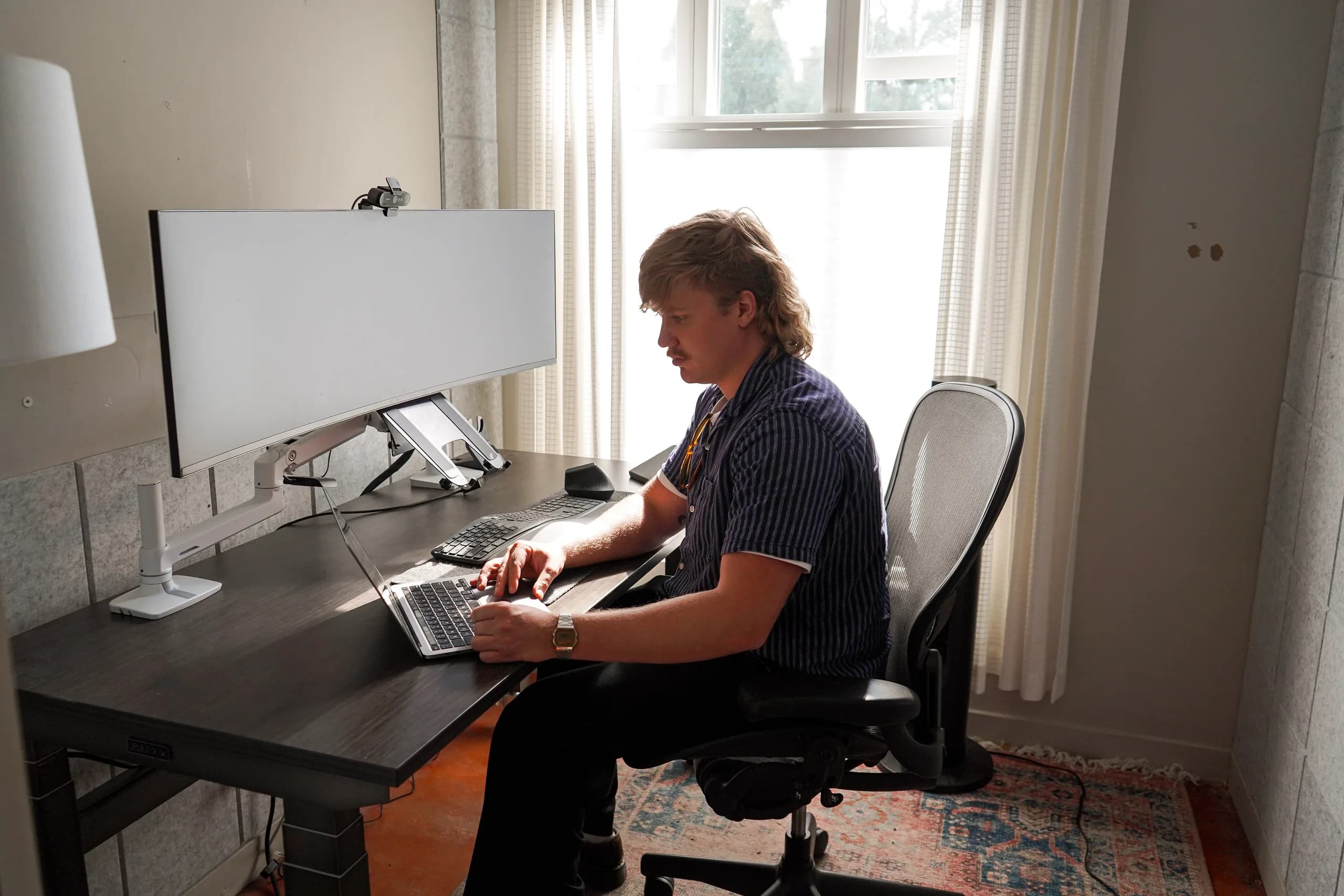 A member working at the ultrawide monitor in a single private office at Merritt Workspace, Sloan's Lake, Denver
