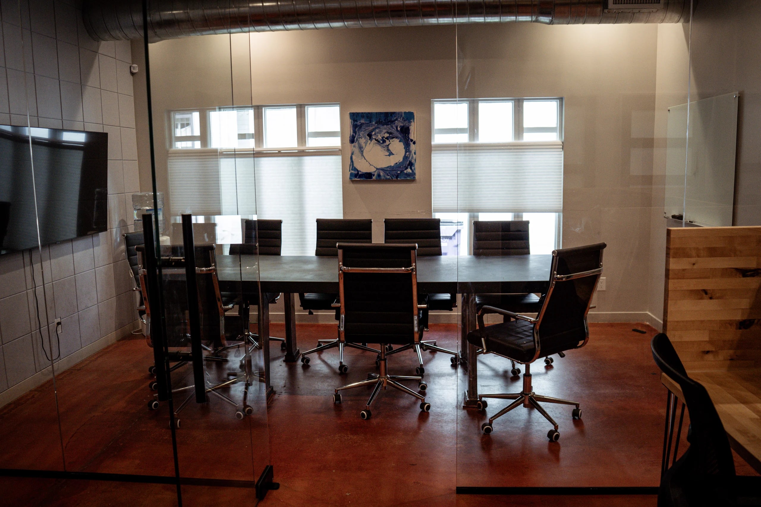 The glass-walled conference room at Merritt Workspace, with a 75-inch screen and seating for eight, in Sloan's Lake, Denver