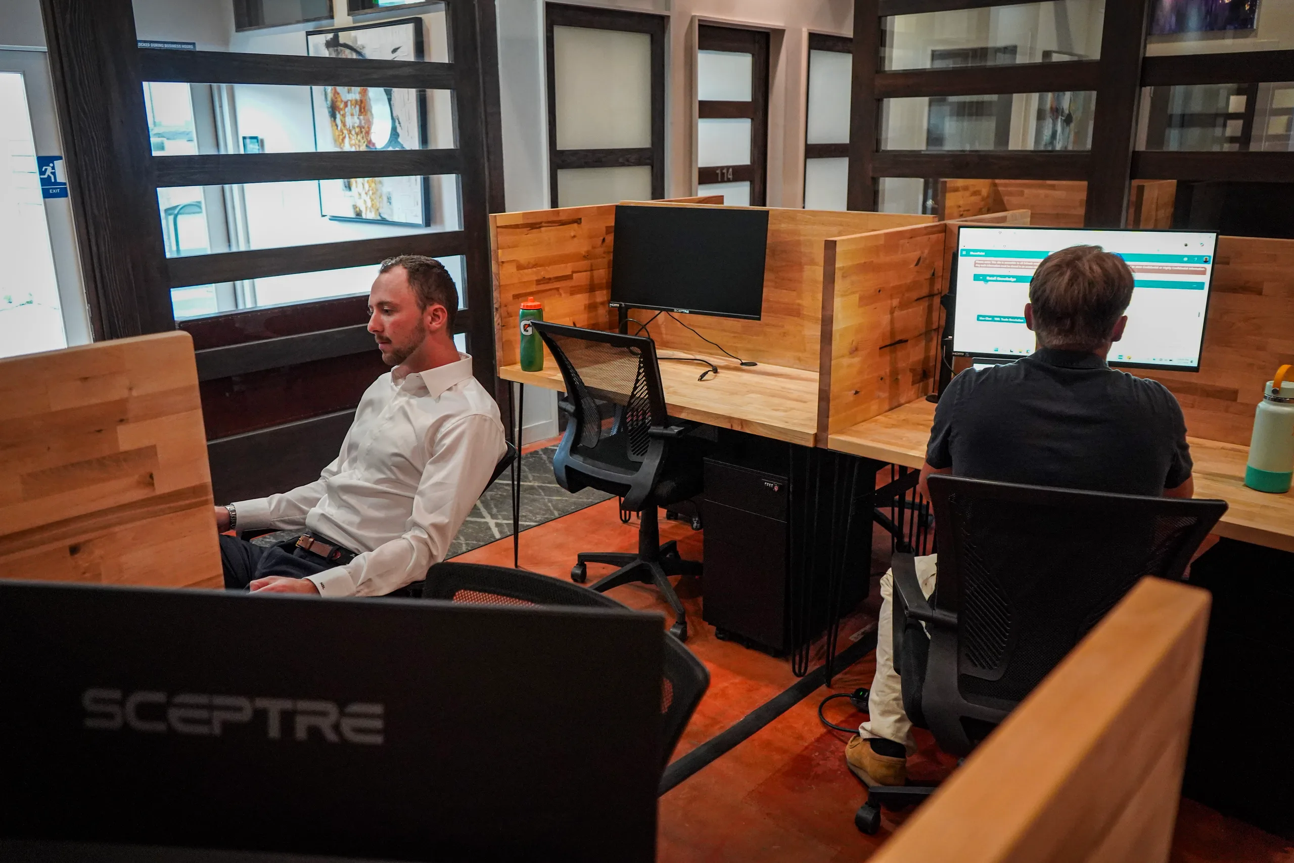 Two members working at their own dedicated desks, with a lockable storage pedestal between the pods, at Merritt Workspace in Sloan's Lake, Denver